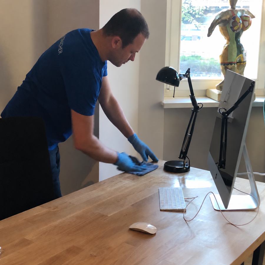 Reinigungskraft von GLANZMACHER wischt einen Schreibtisch in einem Büro in Berlin