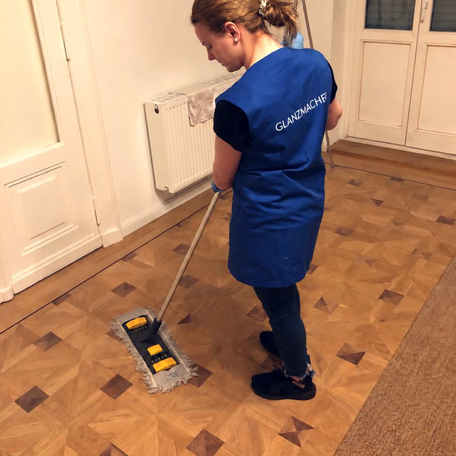 Reinigungskraft von GLANZMACHER reinigt Parkett mit einem Flachmopp in einem Altbau in Berlin
